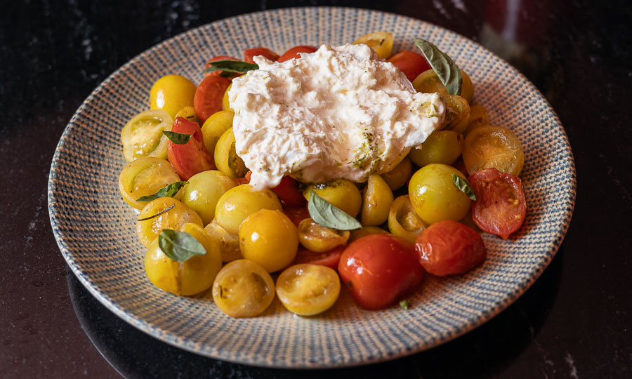 Burrata sobre tomatitos cherry - Caoba Bar