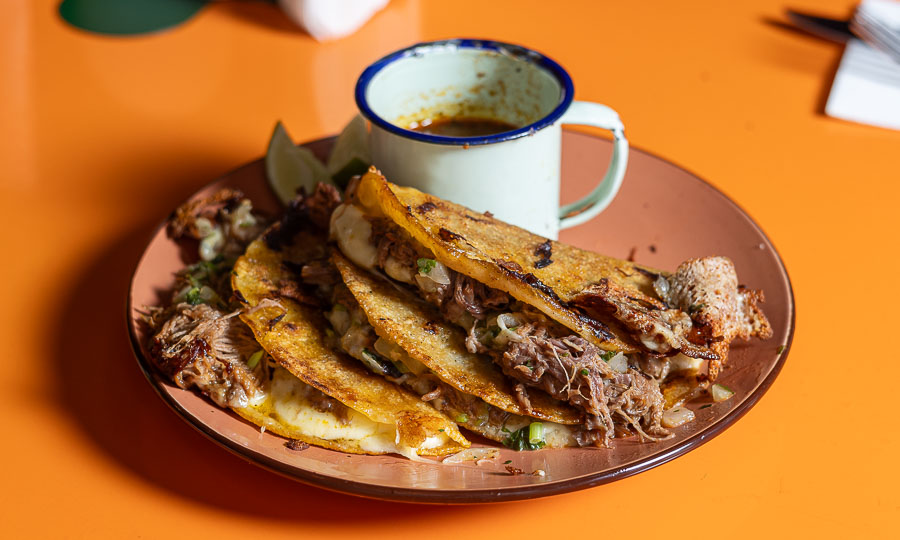 Tres evocadores tacos Birria y queso, con caldo levanta muertos